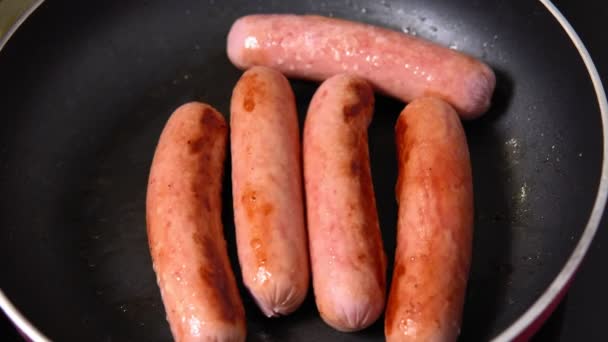Frying sausage in hot olive oil at home kitchen close up. - Footage, Video