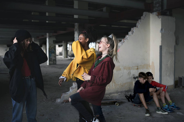 Група підлітків банди, сидячи в приміщенні в покинутій будівлі, розважаються
. - Фото, зображення