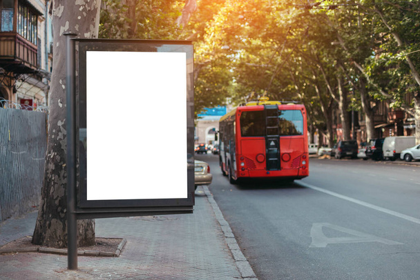 広告のためのブランクスペースの看板モックアップ、通りの道路の近くのバナー。赤いバスは市内の専用線を運行している。 - 写真・画像