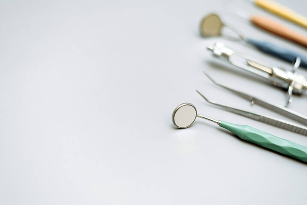Grundlegende Zahnarztwerkzeuge auf hellblauem Hintergrund: Zahnsonde, Brutto-Mayer-Klemme, Zahnspiegel und Explorer. Dentalhygiene und Gesundheitskonzept - Foto, Bild