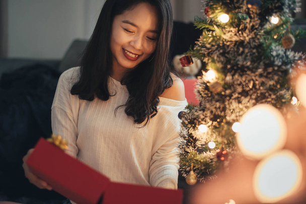 Kobieta niespodzianka i patrząc pudełko prezentów świątecznych w Boże Narodzenie. szczęśliwa dziewczyna z prezentów świątecznych dla świętowania Bożego Narodzenia w domu. - Zdjęcie, obraz