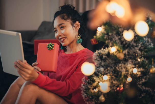 Vrouw maakt videogesprek op sociaal netwerk en geeft kerstcadeau op eerste kerstdag. Gelukkig meisje vieren Kerstmis van sociale netwerk. - Foto, afbeelding