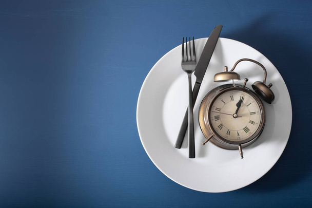концепция прерывистого голодания, кетогенной диеты, потери веса. вилка и нож на тарелке и будильниках - Фото, изображение