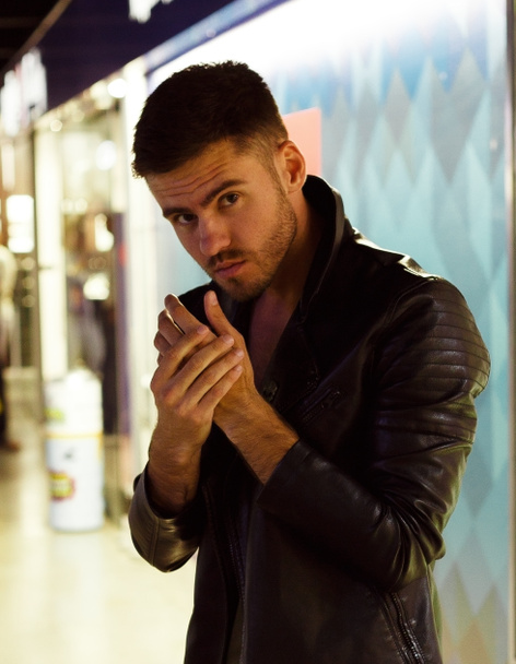 A brutal man in a leather jacket with a cigarette, stubble, brown eyes - Photo, Image