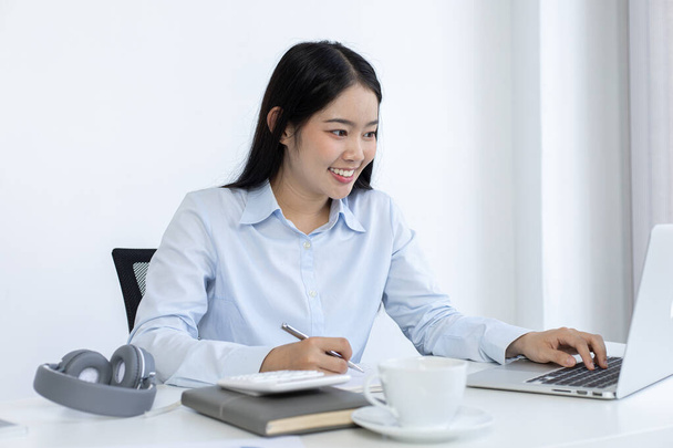 Mujer asiática está estudiando en línea a través de Internet con una sonrisa alegre, quedarse en casa, Nueva normal, Covid-19 coronavirus, distanciamiento social, aprendizaje en Internet. - Foto, imagen