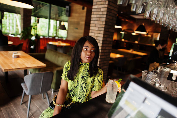 Glamour african american woman wear fashionable snake dress and sunglasses pose on bar. - 写真・画像