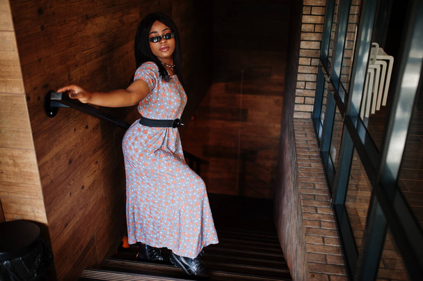 Fashion portrait of african american woman in long dress, boots and sunglasses indoor. - Φωτογραφία, εικόνα