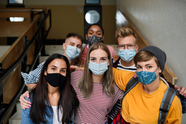 Вид спереду на молодих студентів з масками обличчя в коледжі або університеті, концепція коронавірусу
. - Фото, зображення