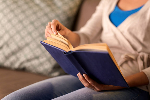 close up of young woman reading book at home - Foto, Imagen