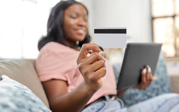 happy woman with tablet pc and credit card at home - Foto, afbeelding