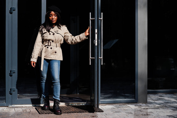 Fashionable african american woman wear beret and coat standing against door. - Foto, afbeelding