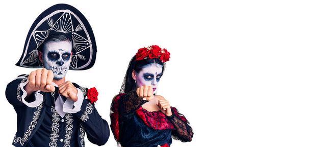 Jeune couple portant le jour mexicain du costume mort sur fond poing poing pour se battre, attaque agressive et en colère, menace et violence  - Photo, image