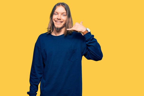 Handsome caucasian man with long hair wearing casual winter sweater smiling doing phone gesture with hand and fingers like talking on the telephone. communicating concepts.  - Photo, Image