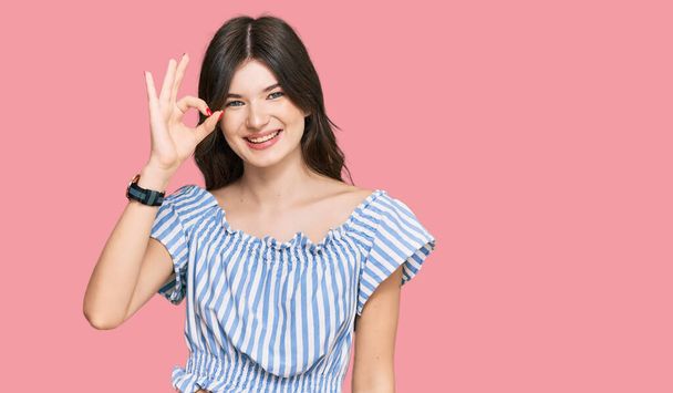 Young beautiful caucasian girl wearing casual clothes smiling positive doing ok sign with hand and fingers. successful expression.  - Photo, Image