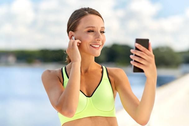 woman with earphones and smartphone doing sports - Photo, image