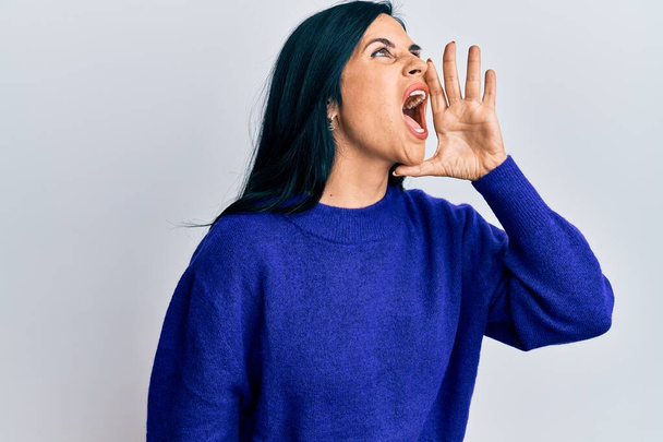 Mulher caucasiana jovem vestindo roupas casuais gritando e gritando alto para o lado com a mão na boca. conceito de comunicação.  - Foto, Imagem