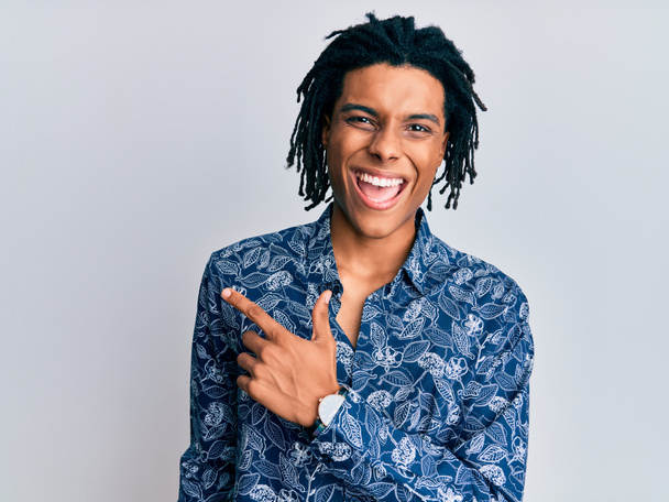 Young african american man wearing 80s style shirt cheerful with a smile of face pointing with hand and finger up to the side with happy and natural expression on face  - Photo, Image