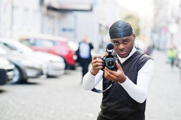 Young professional african american videographer holding professional camera with pro equipment. Afro cameraman wearing black duraq making a videos. - 写真・画像