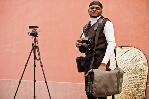 Young professional african american videographer holding professional camera with pro equipment. Afro cameraman wearing black duraq making a videos. - Fotoğraf, Görsel