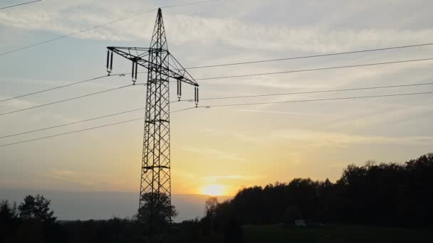 Silueta de una torre de transmisión durante la puesta del sol. Silueta de líneas eléctricas durante la puesta del sol. - Metraje, vídeo