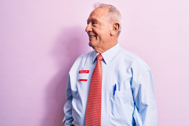 Старший привлекательный седой бизнесмен в галстуке и рубашке с именем презентация наклейка глядя в сторону, расслабиться профиль позировать с естественным лицом и уверенной улыбкой. - Фото, изображение