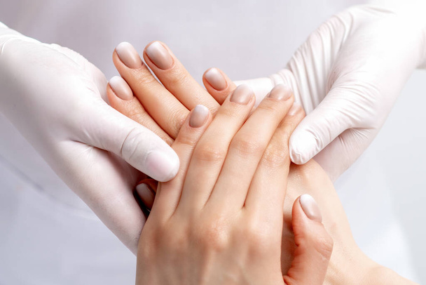Manicure het dragen van handschoenen doen wax massage op vrouwelijke handen met manicure in nagel salon - Foto, afbeelding