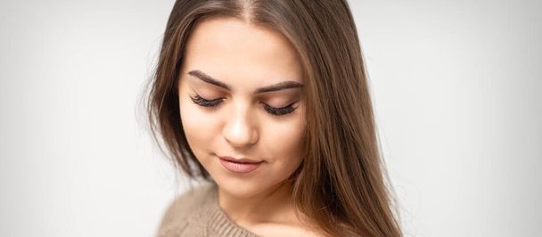 Портрет красивой молодой кавказки с закрытыми глазами после процедуры наращивания ресниц и постоянного макияжа - Фото, изображение