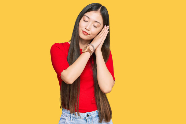 Young chinese woman wearing casual clothes sleeping tired dreaming and posing with hands together while smiling with closed eyes.  - Foto, immagini