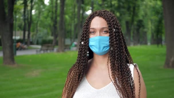 Uzun kıvırcık saçlı kadınlar, bulaşıcı hastalıklara karşı korunmak için koruyucu yüz maskelerini çıkarırlar. - Video, Çekim