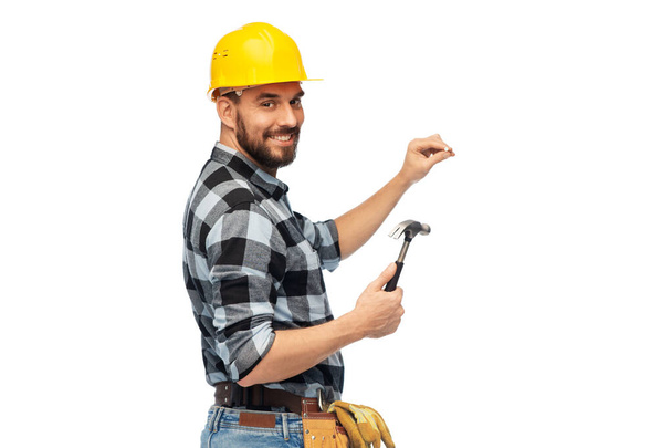 happy male builder in helmet with hammer and nail - Foto, imagen