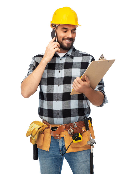 happy builder with clipboard calling on smartphone - Photo, Image