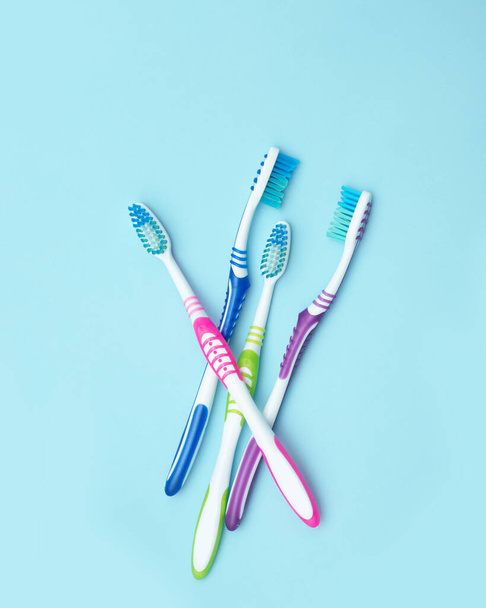 Quattro spazzolini colorati. Gruppo di quattro spazzolini da denti su fondo blu. Il concetto di denti sani in famiglia. Posa piatta - Foto, immagini
