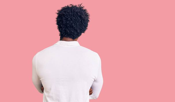 Handsome african american man with afro hair wearing casual clothes and glasses standing backwards looking away with crossed arms  - Фото, изображение