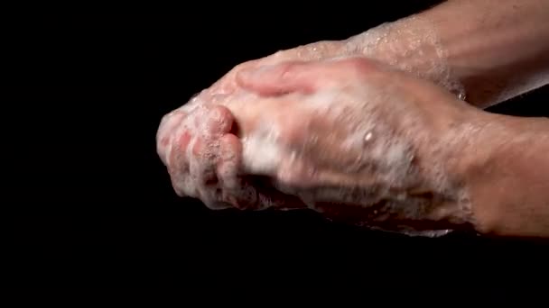 男は石鹸で手を洗う。泡は黒い背景で閉じます。コロナウイルスの概念 - 映像、動画