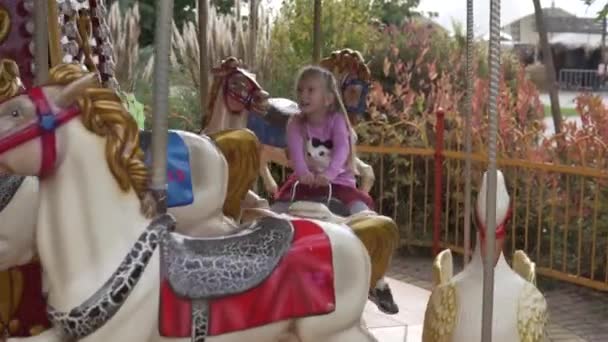 Дети катаются на лошади на качелях в парке развлечений в Хэллоуин - Кадры, видео