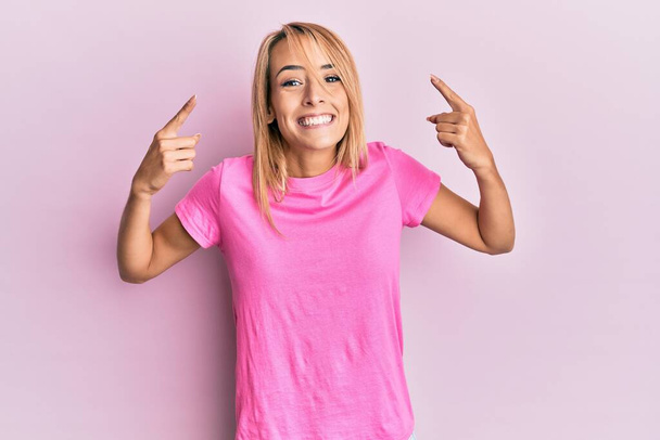 Beautiful blonde woman wearing casual pink tshirt smiling pointing to head with both hands finger, great idea or thought, good memory  - Foto, immagini