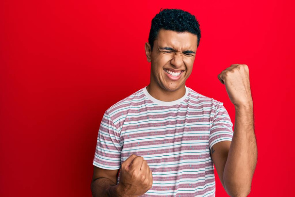 Young arab man wearing casual clothes celebrating surprised and amazed for success with arms raised and eyes closed  - Foto, afbeelding