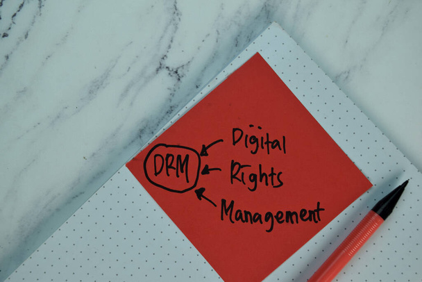 DRM - Digital Rights Management write on sticky note isolated on Wooden Table. - Photo, Image