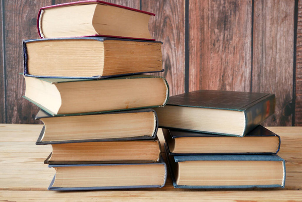 стопка книг на деревянном фоне, много книжных стопок, книжная полка - Фото, изображение