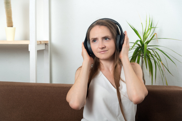 Chica en casa con auriculares escuchando música audiolibro podcasts. - Foto, Imagen