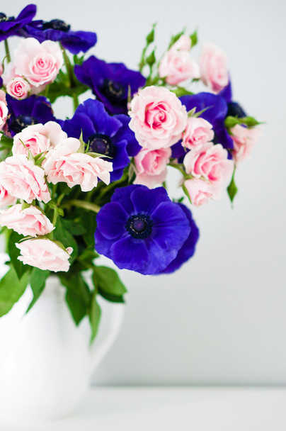 Bouquet of pink roses and blue anemones in white vase - Photo, image
