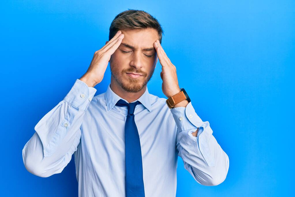 Handsome caucasian man wearing business shirt and tie suffering from headache desperate and stressed because pain and migraine. hands on head.  - Foto, imagen