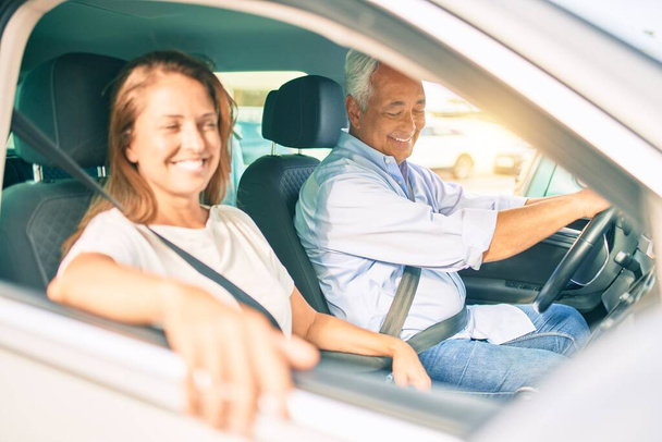 Keski-ikäinen pari rakastunut istuu autossa menossa matkalle hymyillen onnellinen ja iloinen yhdessä - Valokuva, kuva