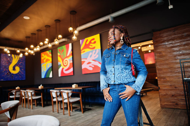 Lovely african american woman with dreadlocks in blue stylish jeans jacket at cafe. Beautiful cool fashionable black young girl indoor. - Fotografie, Obrázek