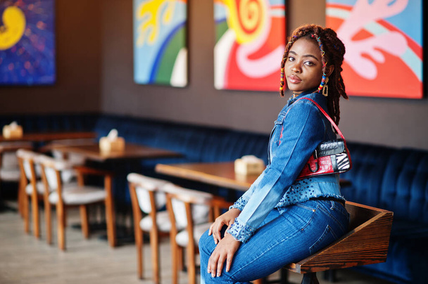 Lovely african american woman with dreadlocks in blue stylish jeans jacket at cafe. Beautiful cool fashionable black young girl indoor. - Φωτογραφία, εικόνα
