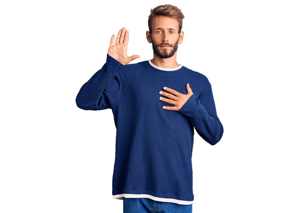 Hombre rubio guapo con barba usando suéter casual jurando con la mano en el pecho y la palma abierta, haciendo un juramento de lealtad promesa  - Foto, Imagen