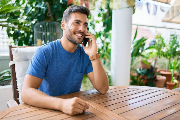 Young hispanic man having conversation talking on the smartphone at the terrace. - Foto, Imagem
