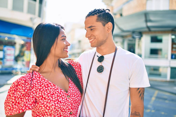 Joven pareja latina sonriendo feliz abrazándose en la calle de la ciudad. - Foto, imagen