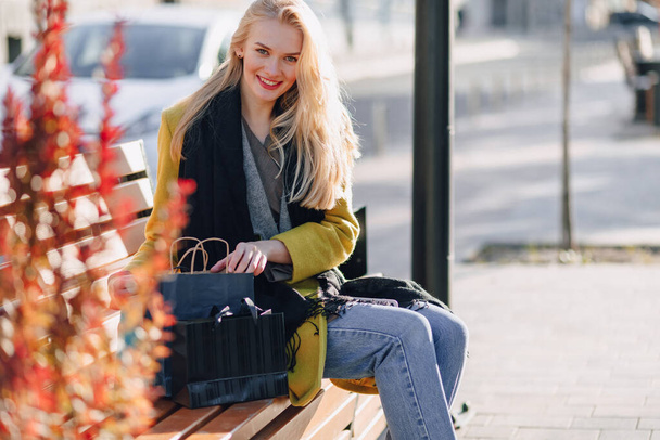 cute happy attractive blonde woman with packages on the street in sunny warm weather. shopping and positive emotions. - Φωτογραφία, εικόνα