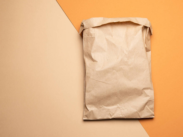 brown paper disposable food bag on a orang background, concept of delivery and ordering, top view, zero waste - Photo, image